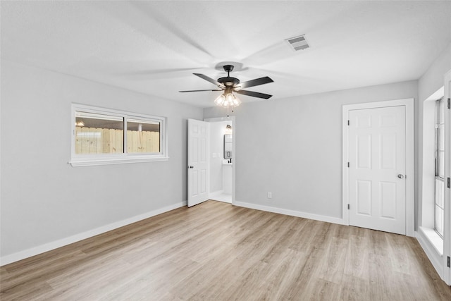 empty room featuring light wood-style floors, visible vents, ceiling fan, and baseboards