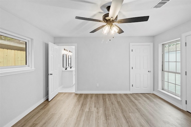 spare room with a ceiling fan, light wood-style flooring, visible vents, and baseboards