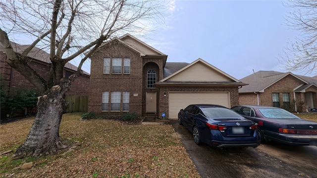 traditional-style home featuring a garage, brick siding, driveway, and fence