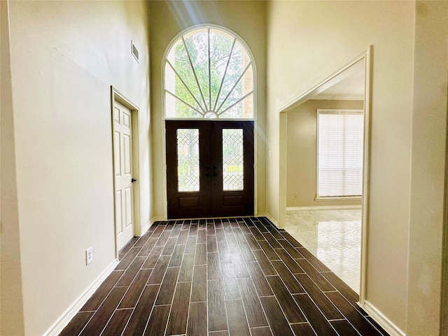 foyer featuring french doors, a towering ceiling, visible vents, and wood tiled floor