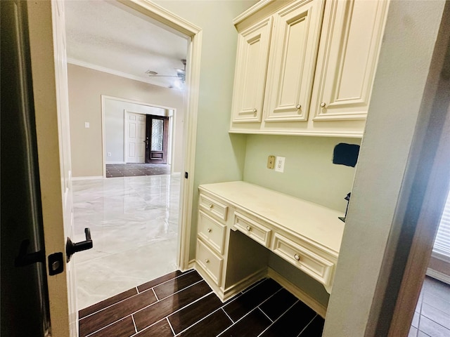 office featuring ceiling fan, ornamental molding, built in desk, and wood finish floors