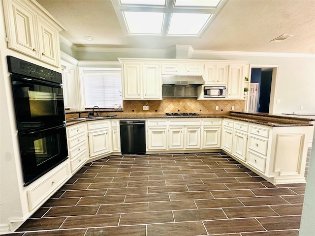 kitchen with a peninsula, black appliances, and cream cabinets