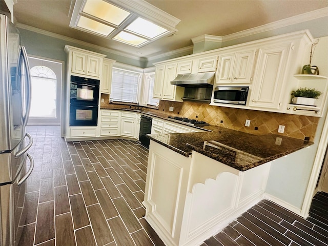 kitchen featuring under cabinet range hood, a peninsula, a sink, wood tiled floor, and black appliances