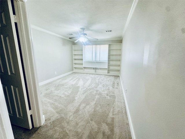 carpeted empty room with baseboards, a ceiling fan, visible vents, and crown molding