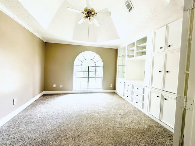 spare room with baseboards, built in shelves, a raised ceiling, and light colored carpet