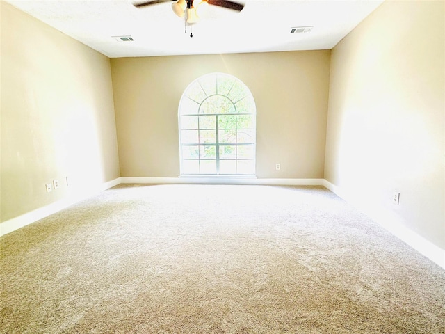 carpeted spare room featuring visible vents and ceiling fan