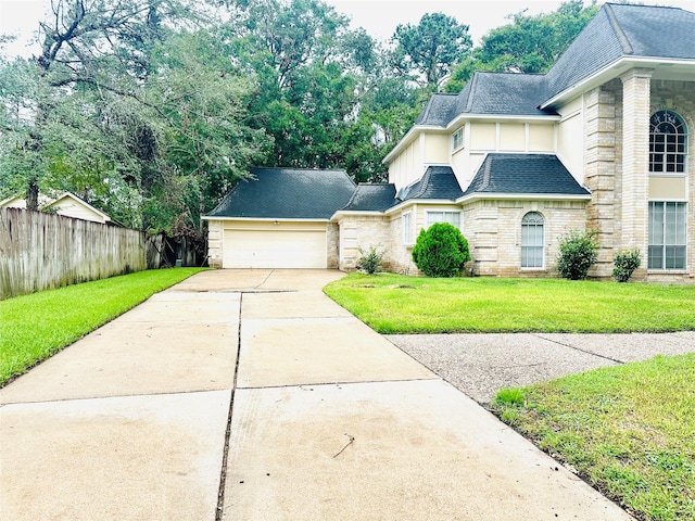 view of front of house featuring roof with shingles, an attached garage, a front yard, fence, and driveway