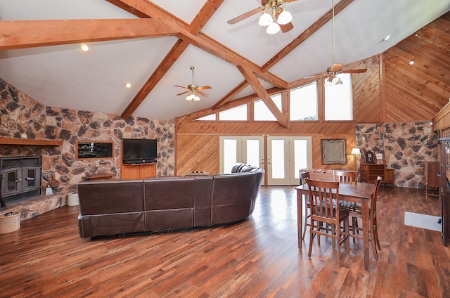 living area featuring a ceiling fan, wooden walls, wood finished floors, high vaulted ceiling, and beamed ceiling