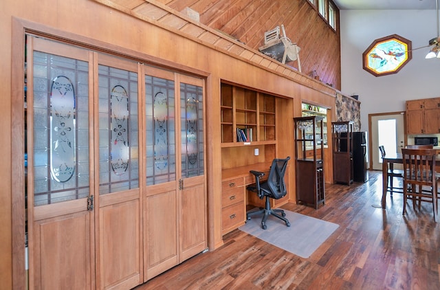 home office featuring dark wood-style floors, high vaulted ceiling, and built in desk