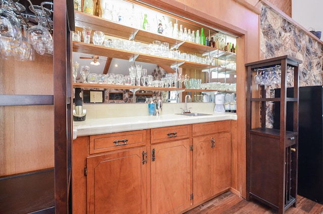 bar featuring a ceiling fan, wet bar, a sink, and wood finished floors