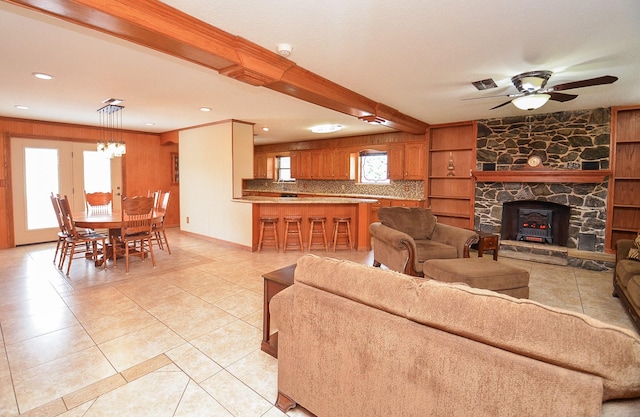 living area featuring light tile patterned floors, visible vents, ceiling fan with notable chandelier, a stone fireplace, and recessed lighting