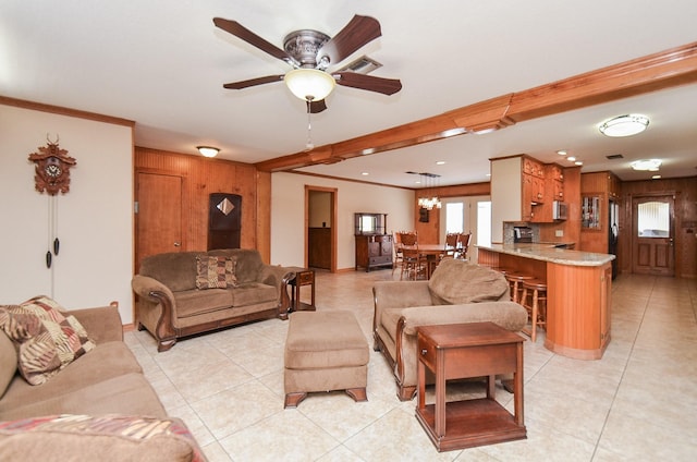 living area with light tile patterned floors, wooden walls, visible vents, and ornamental molding