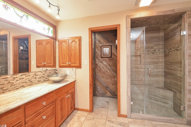 full bathroom with a stall shower, baseboards, vanity, and decorative backsplash