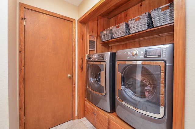 laundry area with laundry area, washing machine and clothes dryer, and light tile patterned floors