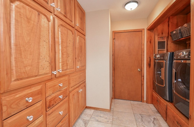 laundry room featuring baseboards, cabinet space, and washing machine and clothes dryer