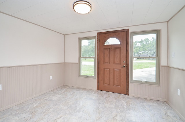 entrance foyer featuring a wainscoted wall and crown molding