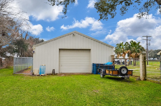 detached garage featuring driveway and fence