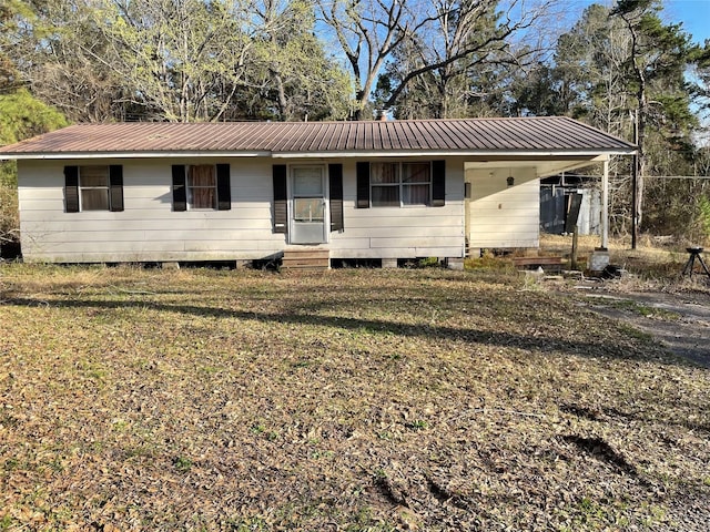 single story home with entry steps, a front lawn, metal roof, and a carport