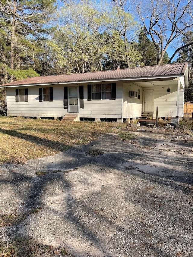 ranch-style home with entry steps, driveway, and metal roof