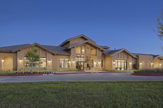 view of front of home featuring stucco siding, driveway, roof mounted solar panels, and a front yard