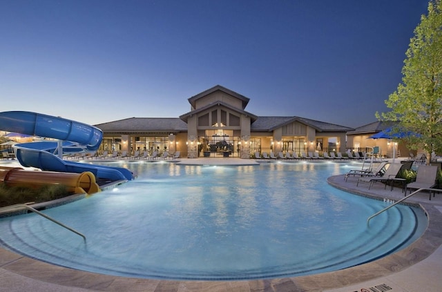 community pool with a patio and a water slide