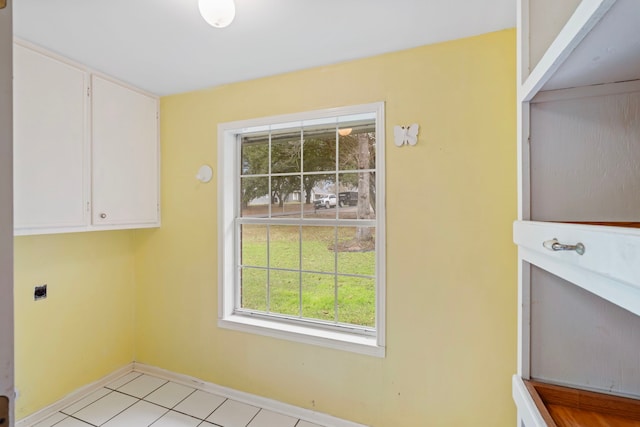 clothes washing area featuring cabinet space, electric dryer hookup, baseboards, and light tile patterned flooring