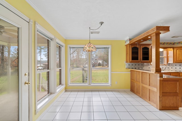 kitchen featuring brown cabinets, decorative light fixtures, crown molding, light tile patterned floors, and visible vents