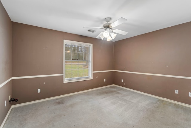 spare room with baseboards, visible vents, a ceiling fan, and light colored carpet