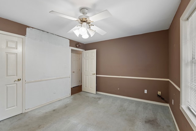 spare room featuring a ceiling fan, light colored carpet, and baseboards