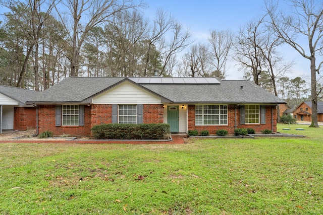 single story home with a shingled roof, a front yard, and brick siding