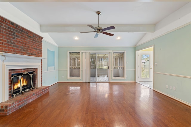 unfurnished living room with a brick fireplace, plenty of natural light, lofted ceiling with beams, and wood finished floors