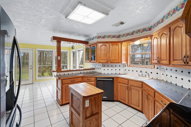 kitchen featuring a sink, a kitchen island, visible vents, black appliances, and glass insert cabinets