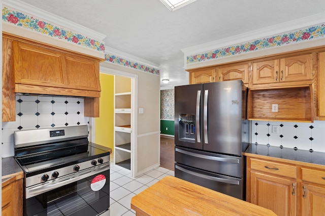 kitchen with dark countertops, ornamental molding, stainless steel appliances, and light tile patterned flooring