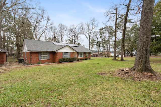 exterior space featuring roof mounted solar panels, brick siding, and a lawn