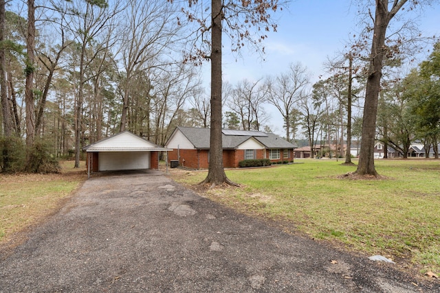 ranch-style house featuring an attached garage, brick siding, an outdoor structure, driveway, and a front yard