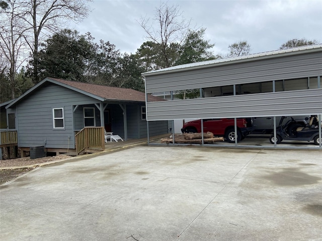 view of front of house with a carport, central air condition unit, and concrete driveway