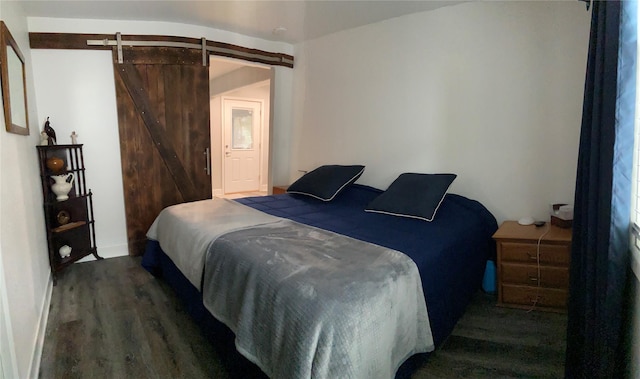 bedroom with dark wood-style floors and a barn door