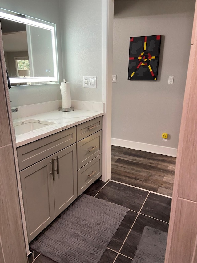 bathroom with wood finished floors, vanity, and baseboards