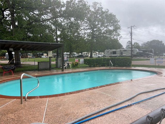 community pool with a patio area and fence