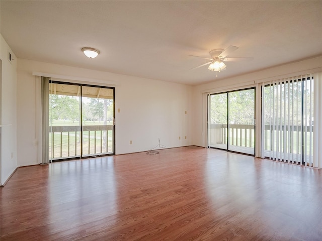 empty room with visible vents, a ceiling fan, and wood finished floors