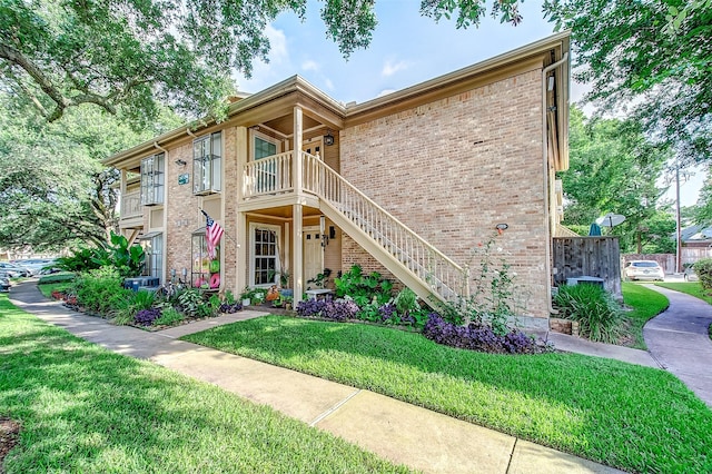 view of front of property with a front yard, brick siding, and stairs