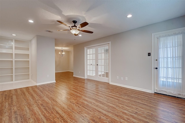 unfurnished room featuring light wood-style flooring, recessed lighting, ceiling fan with notable chandelier, visible vents, and baseboards