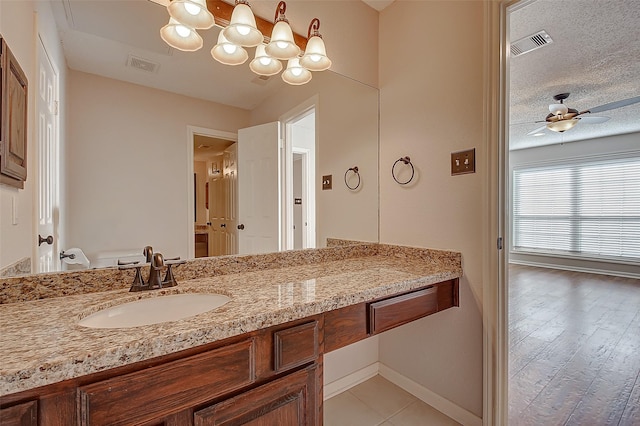 bathroom with a textured ceiling, ceiling fan, vanity, and visible vents