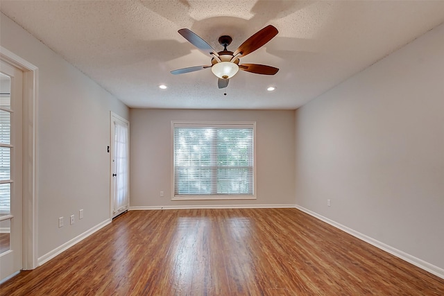 spare room featuring a textured ceiling, ceiling fan, wood finished floors, and baseboards