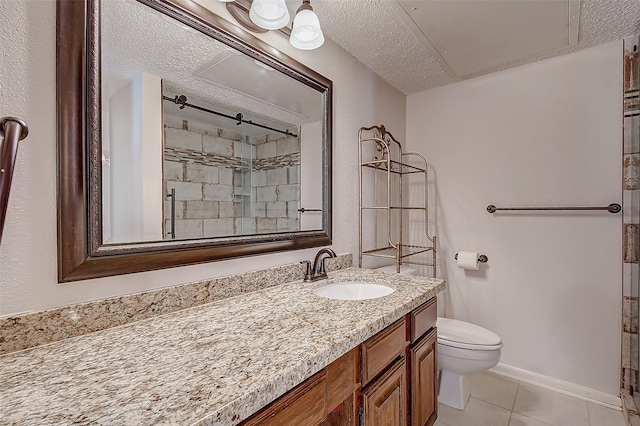 bathroom featuring toilet, a tile shower, vanity, a textured ceiling, and tile patterned floors