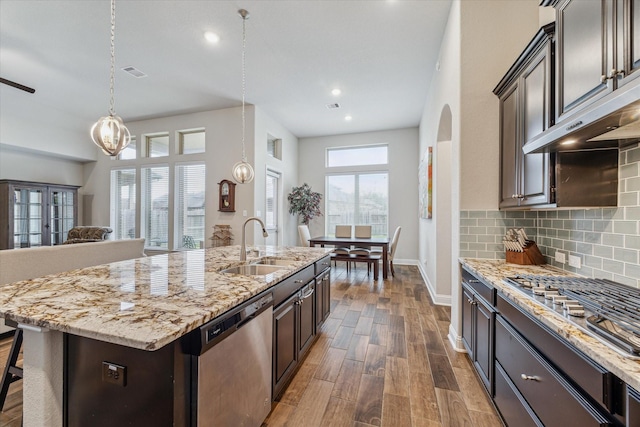 kitchen featuring appliances with stainless steel finishes, dark wood-type flooring, a sink, dark brown cabinets, and backsplash