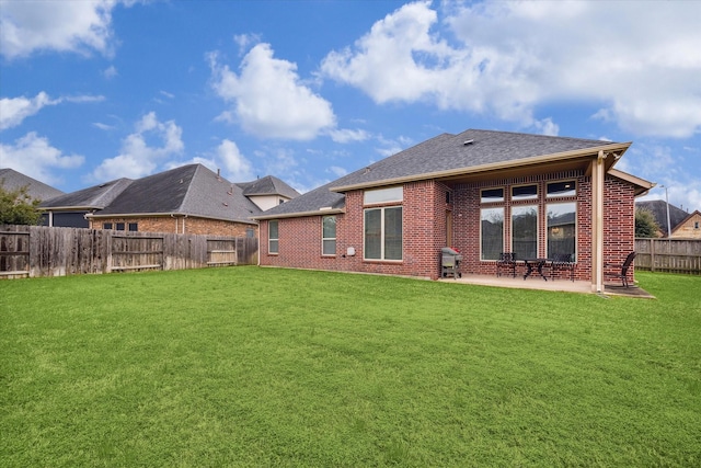 back of house featuring brick siding, a lawn, and a fenced backyard