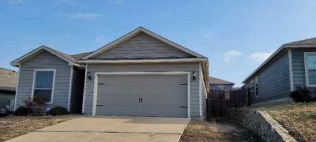 single story home with concrete driveway and an attached garage