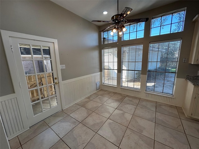 unfurnished dining area featuring a wainscoted wall, light tile patterned floors, visible vents, and a ceiling fan