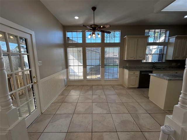 kitchen with light tile patterned floors, wainscoting, a sink, ceiling fan, and dishwasher